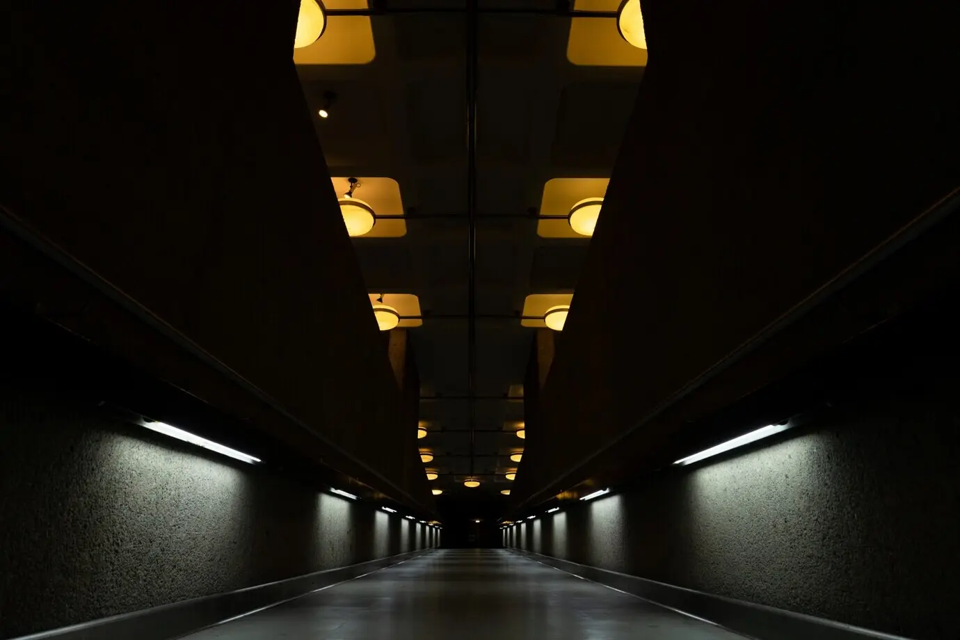A dark tunnel with ceiling lamps turned on