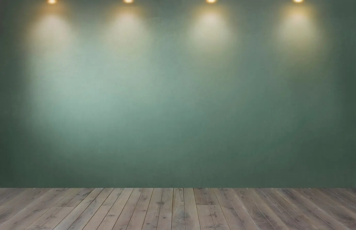 A green wall and a row of spotlights in an empty room.